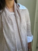 Sweater de punto rosa claro con diseño de capas, que incluye una camisa blanca debajo y un pañuelo a juego con detalles de encaje y flecos en el ruedo.