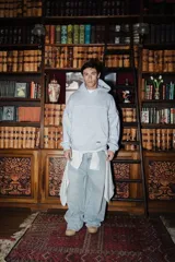 Hoodie de algodón color gris melange, con diseño de costuras decorativas en contraste blanco en el pecho y mangas. Presenta capucha, bolsillo tipo canguro frontal y puños y ruedo acanalados.