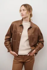 Chaqueta color camel con cuello camisero, cierre frontal con botones dorados, dos bolsillos de parche en el pecho y costuras decorativas en contraste.