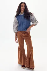 Pantalón de denim color marrón con corte acampanado y diseño de paneles en el ruedo que aporta volumen y movimiento.