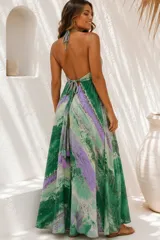 Vestido largo de diseño amplio y fluido, con estampado tipo marmolado en tonos verdes, violetas y blancos. Posee escote halter con tirantes ajustables al cuello y espalda descubierta con tiras cruzadas terminadas en borlas.