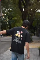 Remera negra de algodón 100% peinado, de corte recto y manga corta. Cuenta con un estampado en la espalda de flores coloridas y la inscripción "Más flores, menos drama".