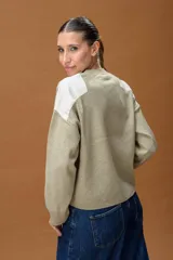 Sweater de punto color beige con cuello redondo y detalles de parches en cuero sintético blanco en los hombros. Presenta mangas largas con puños acanalados y un corte holgado.