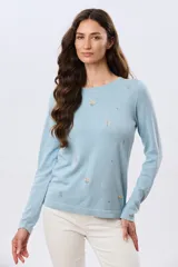 Buzo tejido de algodón color beige, de manga larga, con cuello redondo y delicados motivos bordados distribuidos en la prenda.