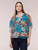 Blusa de gasa semitransparente con hilos de lúrex, estampado floral en tonos azules, blancos y marrones. Cuenta con silueta holgada tipo capa, escote redondo con pequeña abertura en V y detalle de barra metálica. Incluye musculosa interna a tono.