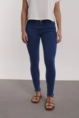 Pantalón de jean azul oscuro, tiro alto, corte skinny y largo al tobillo.