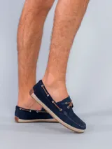 Mocasines estilo náutico de gamuza azul marino con cordones de cuero marrón. Presentan una suela con detalle de yute trenzado alrededor del borde y base de goma.