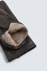 Guantes de cuero negro con interior forrado en tejido de punto. Presentan costuras decorativas en el dorso y tecnología táctil en los dedos para el uso de dispositivos móviles.