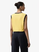 Camiseta sin mangas Adidas de corte cropped, color amarillo con detalles en azul marino en el cuello redondo y las sisas. Incluye el logo del trifolio bordado en el pecho.