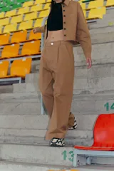 Pantalón de estilo sastrero confeccionado en gabardina elastizada color camel, con corte recto, bolsillos delanteros y tajo en el lateral interno del ruedo.