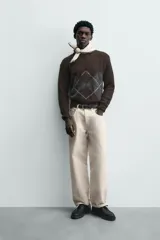 Jersey de punto marrón oscuro con diseño jacquard de rombos en gris y blanco, cuello redondo y manga larga.