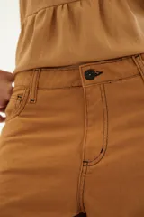 Pantalón de corte recto y tiro medio con costuras a la vista, bolsillos delanteros y traseros, y un detalle de pin de la marca en el ruedo.