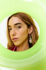 Aros largos con dije colgante de barra dorada y círculos de nácar en tonos lila, verde y blanco.