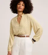 Camisa de viscosa color amarillo, con cuello padre, cierre frontal con botones y mangas largas con puños ajustados. Presenta estampa de follaje y palmeras en tono blanco.