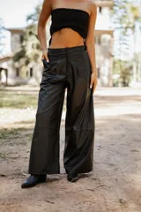 Pantalón de tiro alto confeccionado en cuero sintético, de corte amplio y pierna ancha con costura horizontal a media altura.