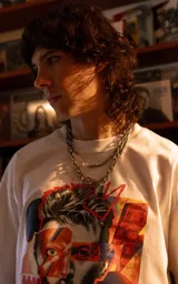 Remera blanca de manga corta y cuello redondo con calce oversize. Presenta un estampado frontal artístico y colorido de David Bowie.