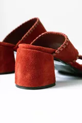 Sandalias tipo mule de taco medio, confeccionadas en cuero gamuzado color terracota. Presentan dos tiras anchas con detalles de costuras pespunteadas en los bordes y taco cuadrado estable.
