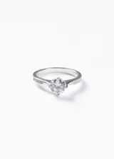 Anillo de plata 925 con diseño de solitario, presenta una zirconia central de corte brillante engarzada en cuatro puntas y detalles de pequeñas zirconias incrustadas en los laterales del aro.