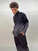 Camisa de lana color gris con cuello mao, corte recto y mangas largas con detalle texturizado. Presenta cierre invisible en el escote superior y tajos laterales.