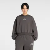 Buzo de cuello redondo New Balance, confeccionado en tejido de vellón de algodón cepillado. Presenta un diseño de corte extragrande con mangas largas y puños ajustados. Incluye un gráfico bordado con puntada de satén en el centro del pecho.