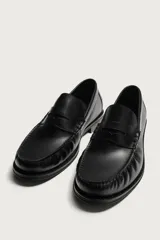 Mocasín de vestir color marrón oscuro, fabricado en cuero, con detalle de antifaz en el empeine y suela a tono con ligero tacón.