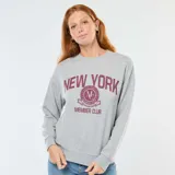 Buzo de cuello redondo en color gris melange, con mangas largas y corte holgado. Presenta un estampado frontal con la inscripción 'NEW YORK' y un logo circular estilo universitario con el texto 'MEMBER CLUB' en color bordó.
