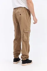 Pantalón cargo color tostado de corte amplio, con cintura elástica y cordón ajustable. Cuenta con bolsillos laterales con tapa en las piernas y puños elastizados en los tobillos.