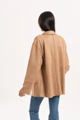 Blazer de estilo oversize confeccionado en material simil gamuza, con cuello solapa, cierre frontal de dos botones y bolsillos laterales con solapa.