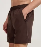 Bermuda deportiva de hombre color marrón, con cintura elástica ajustable mediante lazo y estampa heat print. Confeccionada en tejido de poliéster de secado rápido, diseñada para brindar comodidad y libertad de movimiento durante la actividad física.