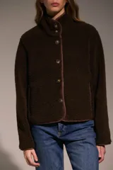 Campera de corderito color marrón, con cuello alto, cierre frontal con botones y terminaciones con ribete al tono.