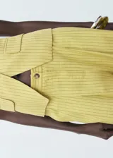Pantalón de tiro alto color amarillo con sutil diseño de rayas verticales, de corte recto y largo, con bolsillos laterales y cierre frontal de botón y cremallera.