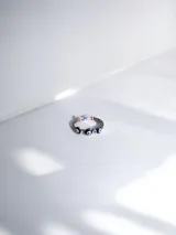 Anillo de acero quirúrgico con diseño de ojos turcos intercalados con pequeñas piedras brillantes.