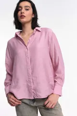 Camisa oversized color rosado, con abotonadura frontal y en las mangas. Presenta un corte vertical en la espalda con lazos decorativos.