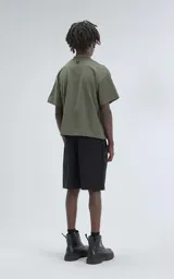 Remera de manga corta y cuello redondo, color verde militar, con calce boxy fit, caracterizada por ser ligeramente más corta y tener mangas amplias.