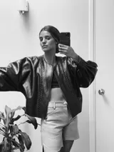 Campera de cuero con silueta oversize y corte levemente corto. Presenta cierre frontal metálico, cuello a la base y mangas amplias. Incluye recortes y detalles trenzados en el delantero que aportan textura.