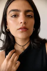 Collar con dije de acero quirúrgico en forma de flor de lirio, montado sobre un tiento de cuero encerado largo.
