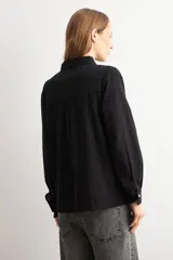 Camisa blanca de manga larga con frente de tela broderie con diseño de rombos calados y espalda lisa. Presenta cuello clásico y cierre frontal con botones.