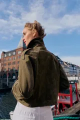 Trench corto de Zara confeccionado en piel de ante, con cuello de solapa, cierre frontal cruzado con botones, mangas largas con trabillas y bolsillos delanteros de vivo.