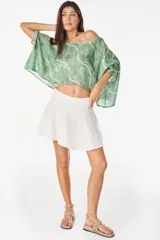 Blusa de lino italiano color blanco, con diseño holgado, escote asimétrico estilo off-shoulder y mangas cortas amplias.