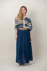 Pollera larga color azul marino con diseño plisado y textura ligera, acompañada de un cinturón rústico trenzado con hebilla redonda.