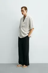 Camisa tipo kimono de corte relaxed fit, color celeste, confeccionada en tejido fluido de viscosa y lino. Presenta cuello con solapas de muesca, manga corta y cierre frontal cruzado con doble botonadura.