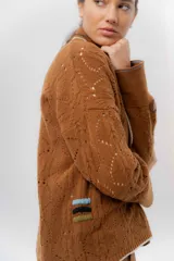 Saco tejido de lambswool color marrón, con diseño inspirado en kimono, mangas largas y delicados calados en toda la prenda. Cuenta con bordes en contraste.