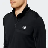 Remera deportiva New Balance de manga larga y cuello alto con cierre parcial, color negro, con logo NB reflectante en el pecho.