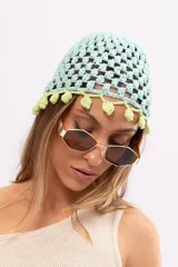 Gorro tipo casquete tejido a mano en hilo de algodón color celeste con borde de pompones verdes.
