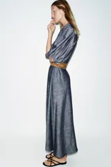 Vestido midi de denim azul con cuello camisero, mangas abullonadas y cierre frontal oculto con botones. Incluye un cinturón marrón con hebilla metálica.