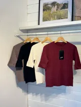 Sweater de tejido de punto con textura de ochos, color blanco, de cuello redondo y mangas cortas.