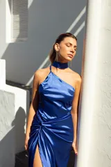 Vestido midi de satén color violeta, con escote asimétrico, falda con abertura lateral y detalle drapeado en la cintura. Incluye un cuello tipo choker que se puede usar de diferentes formas.