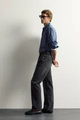 Jeans straight fit de corte recto y tiro medio, confeccionados en denim de algodón rígido con efecto lavado en color negro, de la colección especial Aaron Levine x Zara. Presentan diseño clásico de cinco bolsillos y cierre frontal con botonadura.