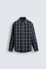Camisa de corte relajado confeccionada en tejido fluido de cupro y viscosa, con estampado de cuadros, cuello solapa, manga larga con puño abotonado y cierre frontal de botones.