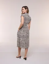 Vestido midi camisero de caída fluida en color beige con estampado de lunares negros. Posee cuello camisero clásico, abotonadura frontal completa, mangas cortas caídas y pinzas en la cintura. Incluye bolsillos laterales y falda evasé.